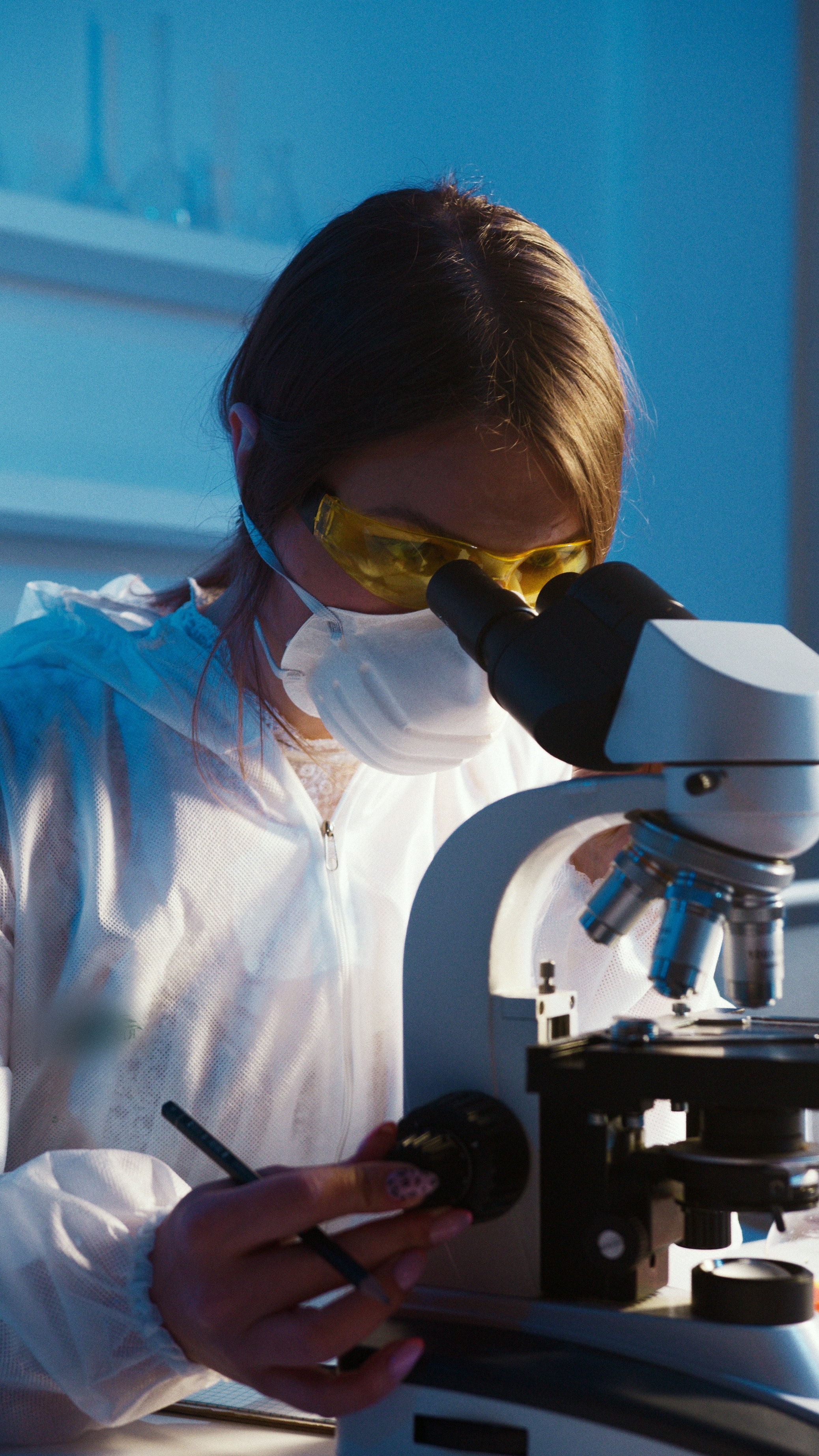 se eria una mujer vestida de laboratorio mirando  a traves de un microscopio